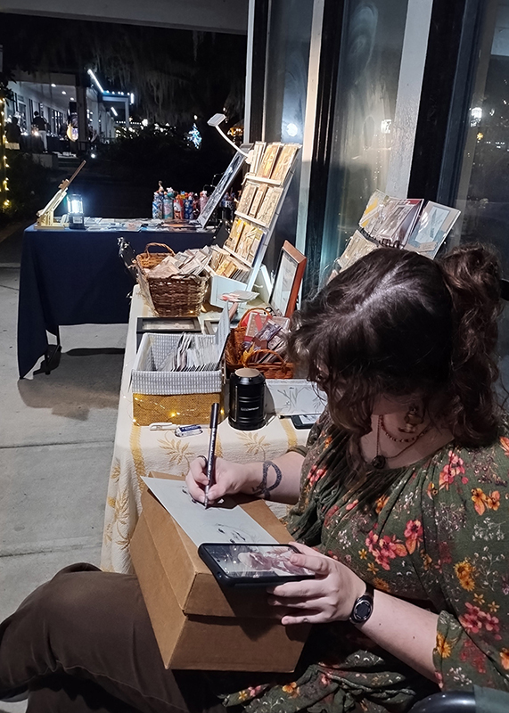 Miranda drawing a 20-minute portrait at a market